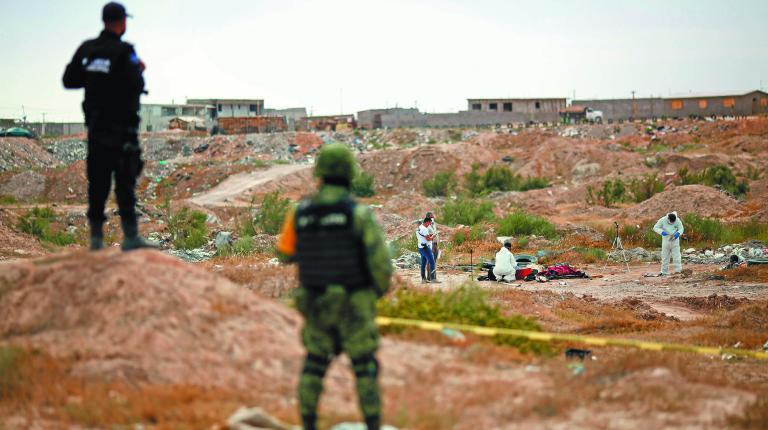 Forensic technicians work at the crime scene where unknown assailants left the bodies of a woman and a man wrapped in blankets, in Ciudad Juarez