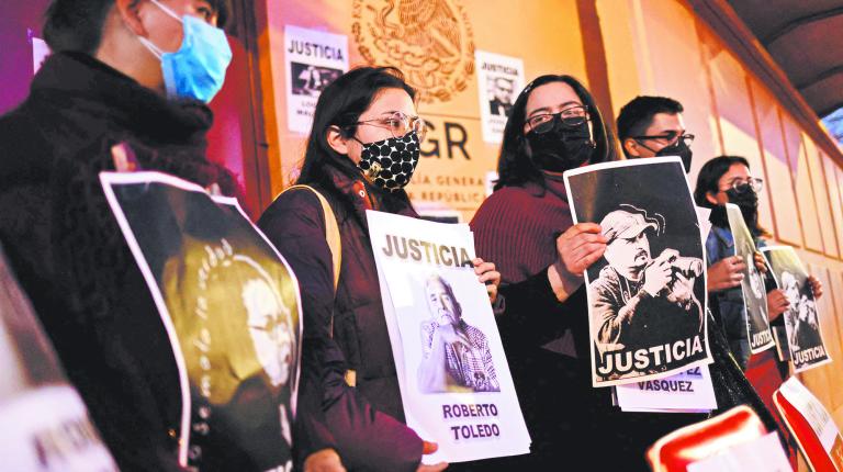 Journalists hold signs portraying murdered journalists and reading 