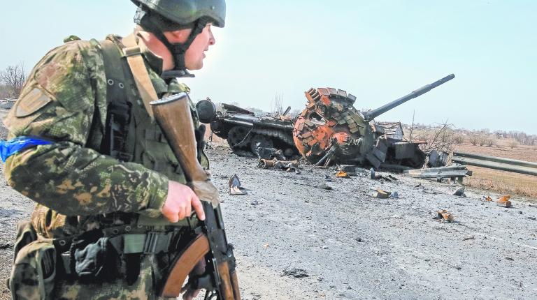 A Ukrainian serviceman stands near the wreck of a Russian tank on the front line in the Kyiv region