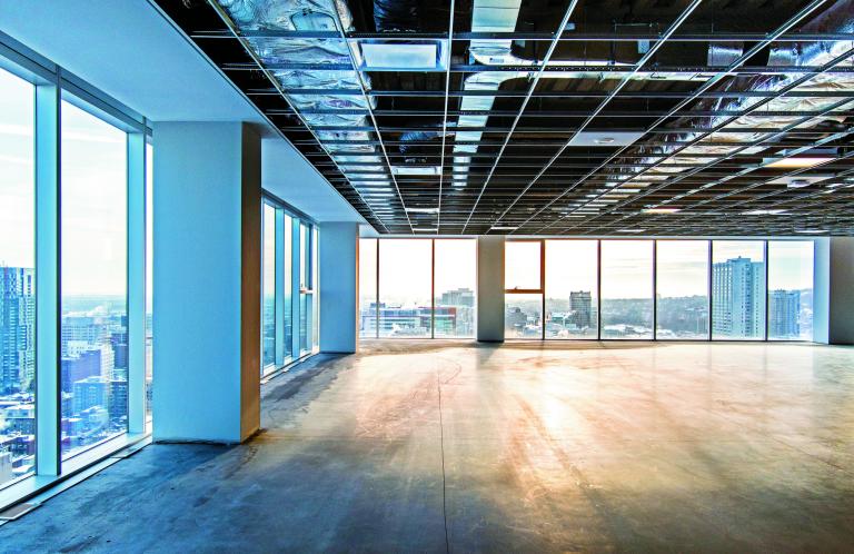 Vacant office space offering views of the city. Open ceiling showing ventilation system. Shot just after construction was completed on a late winter afternoon in downtown Montreal, Quebec, Canada.