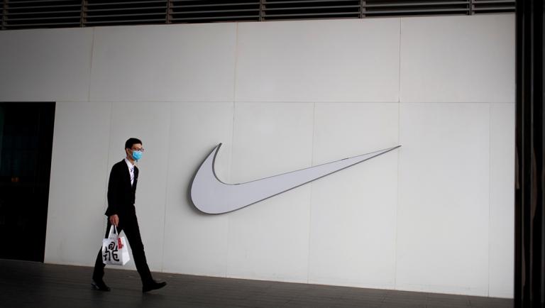 A man wearing a face mask passes a Nike store, as the country is hit by the novel coronavirus outbreak, in Beijing, China, March 2, 2020. REUTERS/Thomas Peter