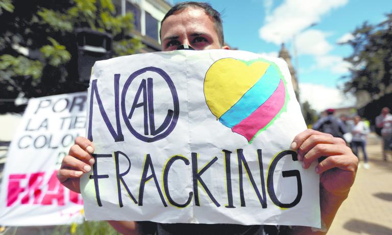 FILE PHOTO: A man holds a sign that reads: "No to fracking", during a protest against the use of fracking, in Bogota