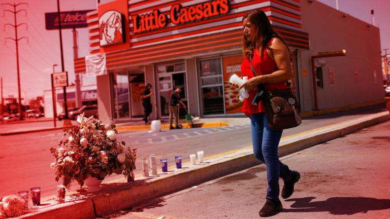 Una mujer lleva una vela a la escena donde mataron a los empleados de Mega Radio, incluido un locutor, mientras estaban afuera de una pizzería. Foto: Reuters