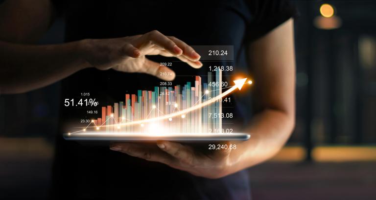 Businessman holding tablet and showing a growing virtual hologram of statistics, graph and chart with arrow up on dark background. Stock market. Business growth, planing and strategy concept.