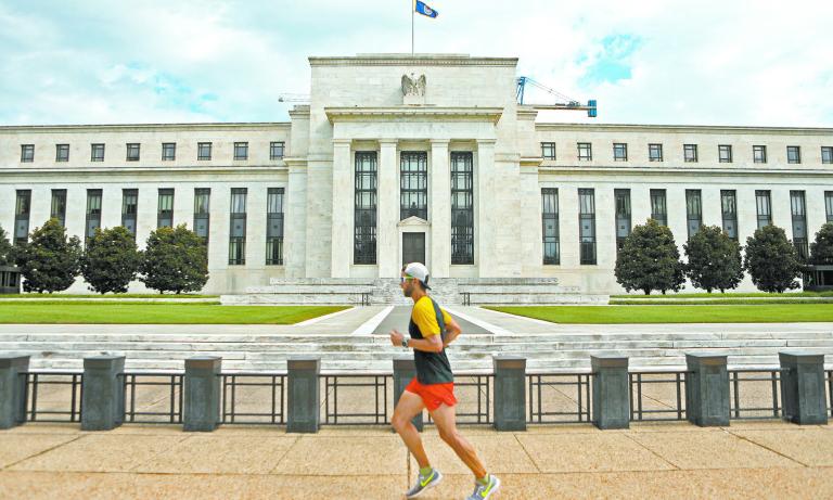 FILE PHOTO: A jogger runs past the Federal Reserve building in Washington, DC