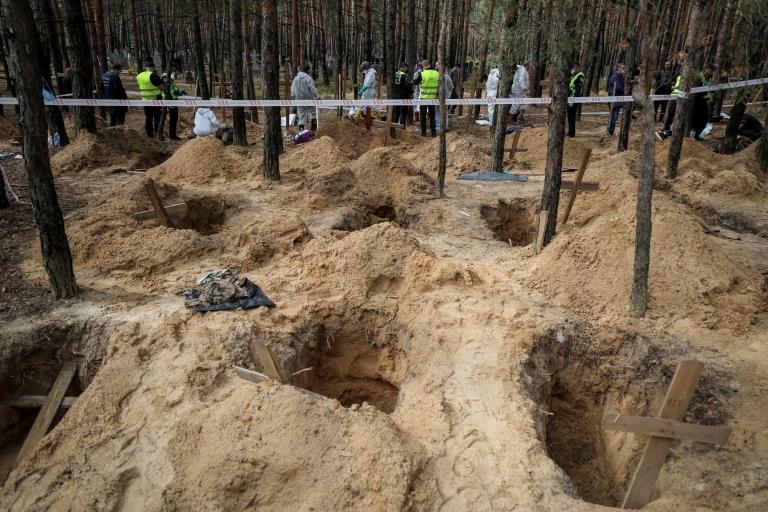 Expertos trabajan en la exhumación de cuerpos encontrados en fosas comunes cerca de Izium, Ucrania. Foto: Reuters