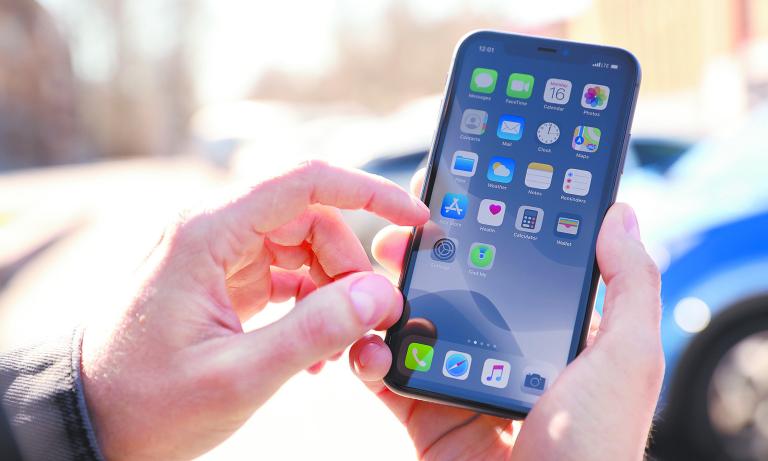 MYKOLAIV, UKRAINE - MARCH 16, 2020: Man holding iPhone 11 with home screen outdoors, closeup