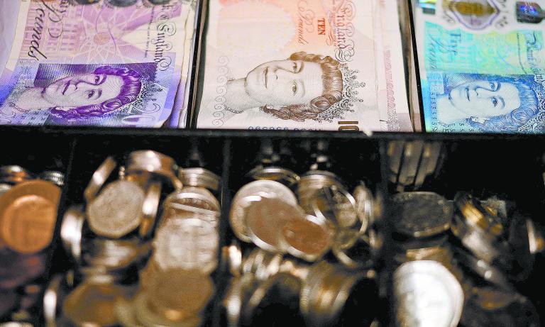 FILE PHOTO: Pound notes and coins are seen inside a cash register in a bar in Manchester, Britain