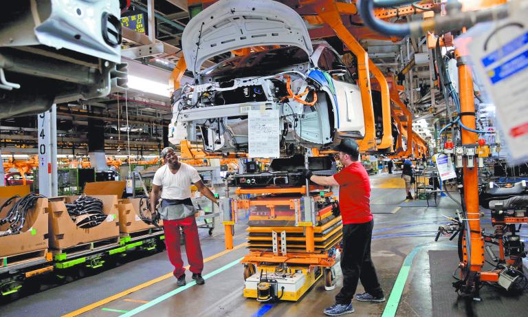 FILE PHOTO: General Motors assembly workers connect a battery pack underneath a partially assembled Chevrolet Bolt EV vehicle