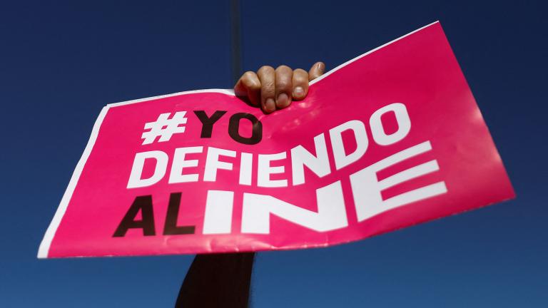 A person holds up a banner that reads