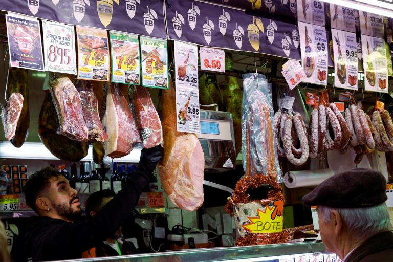 Un comerciante maneja conservas de carne mientras un cliente espera en un supermercado, cuando el gobierno español anuncia medidas para combatir la inflación, en Madrid. Foto: Reuters.