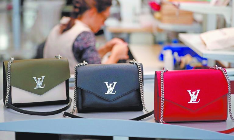 FILE PHOTO: Louis Vuitton handbags are displayed as an employee works in a Vuitton new high-end garment factory in Beaulieu-sur-Layon