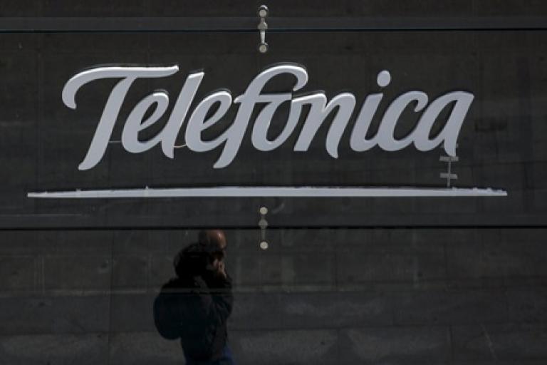 A reflection of a man talking on his phone is seen outside Telefonica's flagship store in central Madrid, Spain, April 28, 2015. Telefonica's move to hike prices in Spain is a bold bet that could finally draw a line under a six-year slump, cut the firm's reliance on Latin America and give it a leg up over rivals on the lucrative premium telecoms market, sources and analysts say. The telecoms giant, whose revenues have dropped 13 percent worldwide and 42 percent in Spain since 2008, has focused on fewer markets, cut debt and invested in new high-speed networks and exclusive television contents to try and regain its mojo. Picture taken on April 28, 2015.  To match story TELEFONICA-SPAIN/PRICES      REUTERS/Sergio Perez