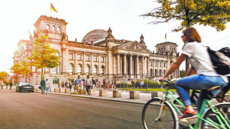 Urban city life with famous Reichstag building in the background in beautiful golden evening light at sunset in summer with retro vintage Instagram style pastel toned filter effect, Berlin, Germany