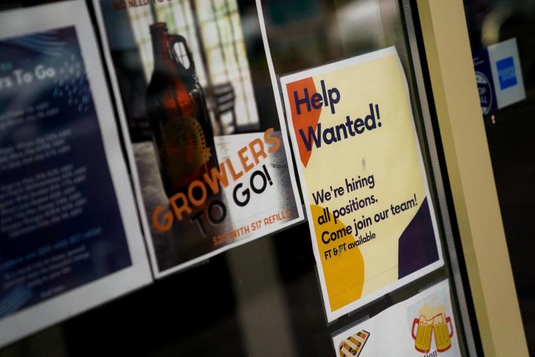 FILE PHOTO: An employee hiring sign is seen in a window of a business in Arlington