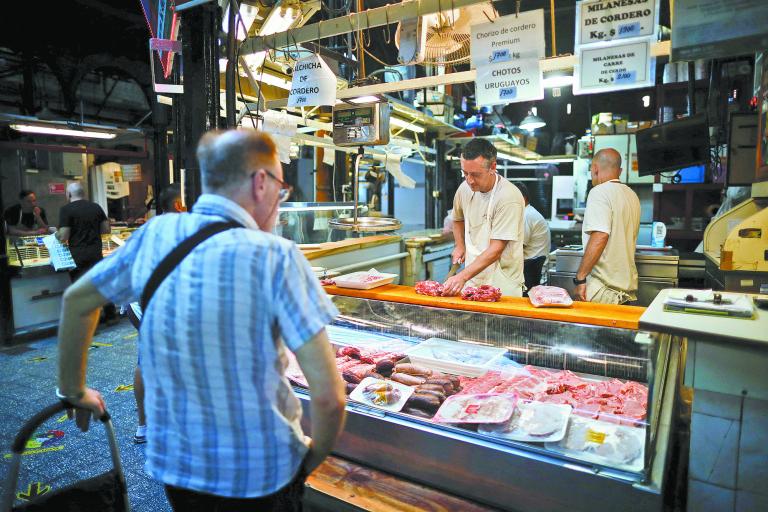 A butcher chops pork meat as a customer waits in a local market, as Argentina's annual inflation rate tore past 100% in February, the country's statistics agency said on Tuesday, the first time it has hit triple figures since a period of hyperinflation in 1991, over three decades ago, in Buenos Aires, Argentina March 14, 2023. REUTERS/Agustin Marcarian