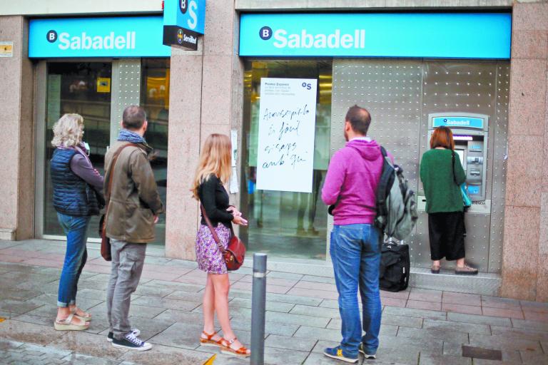 People line up at a Sabadell Bank ATM machine in Barcelona to withdraw money as part of an action to protest the transfer of the bank's headquarters out of Barcelona, Spain, October 20, 2017. REUTERS/Ivan Alvarado