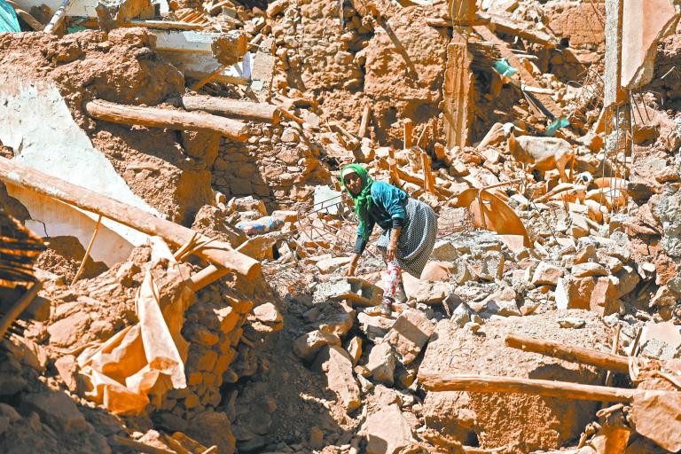 Una mujer camina sobre los escombros intentando rescatar a su cabra tras el terremoto. Foto: Reuters