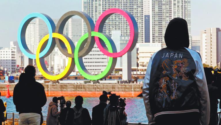 FILE PHOTO: Bystanders watch as giant Olympic rings are reinstalled at the waterfront area at Odaiba Marine Park, after they were temporarily taken down in August for maintenance amid the coronavirus disease (COVID-19) outbreak, in Tokyo, Japan December 1, 2020. REUTERS/Kim Kyung-Hoon/File Picture-NARCH/NARCH30