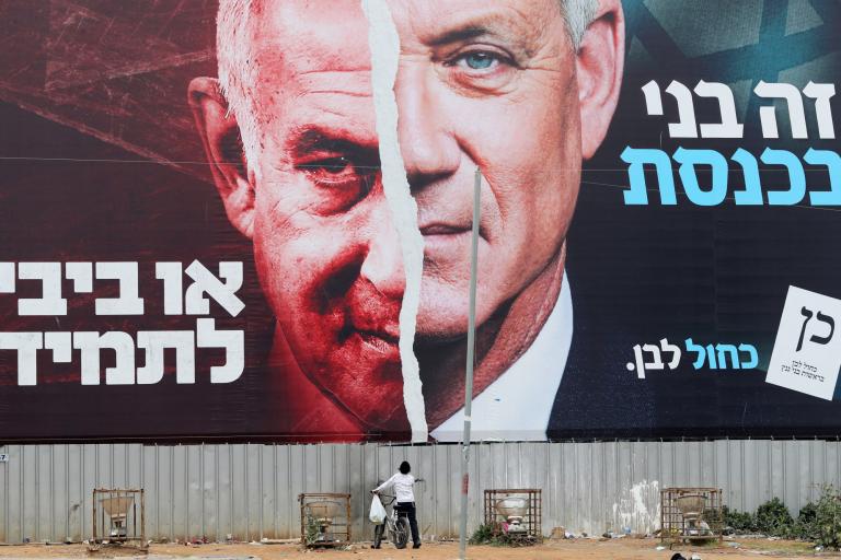 Un niño mira una pancarta de la campaña electoral del partido Azul y Blanco que muestra a su líder, el ministro de Defensa israelí Benny Gantz, junto al Primer Ministro israelí Benjamín Netanyahu. Foto: Reuters.