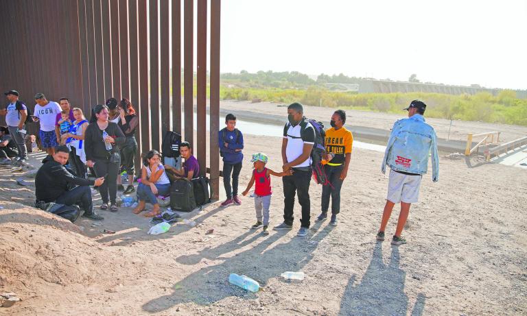 Migrants from Haiti, seeking asylum in the U.S., join others waiting next to the border wall separating the U.S. and Mexico, as they wait to be processed near Yuma, Arizona, U.S., April 30, 2022. Picture taken April 30, 2022. REUTERS/Katie McTiernan  NO RESALES. NO ARCHIVES-NARCH/NARCH30