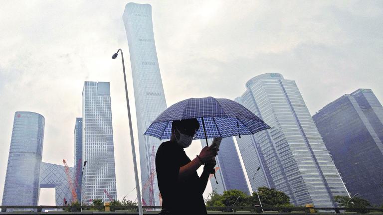 FILE PHOTO: A man walks in the Central Business District on a rainy day, in Beijing