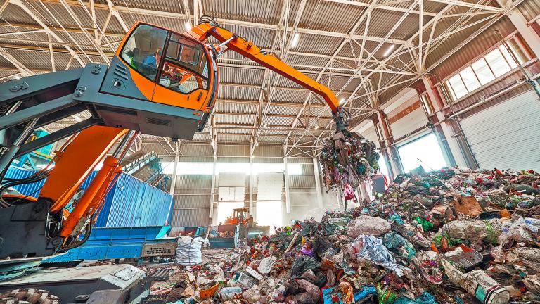 Excavator,Grabs,Trash,In,Warehouse,Of,Waste,Processing,Plant