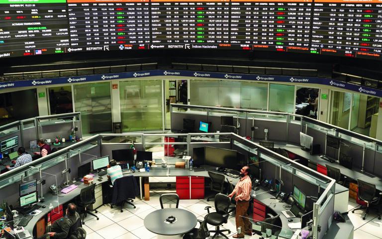 Employees work at their positions as a ticker displays stock exchange data at Mexico