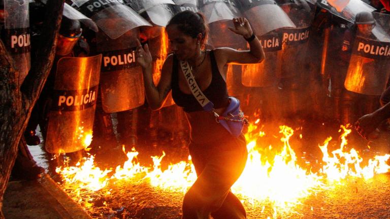 Un manifestante reacciona cuando bombas molotov caen al suelo frente a las fuerzas de seguridad durante las protestas contra los resultados electorales en Venezula. Foto: Reuters