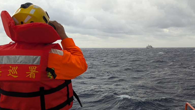 Esta fotografía tomada entre el 7 y 8 de diciembre de 2024 y publicada el 9 de diciembre por la Guardia Costera de Taiwán muestra a un miembro de la tripulación a bordo de un barco de la Guardia Costera de Taiwán monitoreando un barco de la guardia costera china en aguas al este de Taiwán.