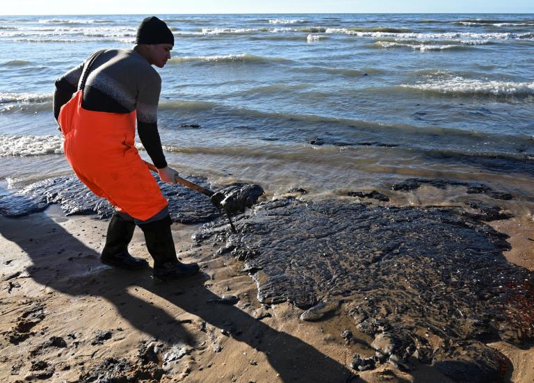 Un voluntario trabaja para limpiar el petróleo derramado en la costa tras un incidente que involucró a dos petroleros dañados por una tormenta en el estrecho de Kerch, en la aldea de Vityazevo, cerca de la localidad de Anapa, en el Mar Negro, Rusia.