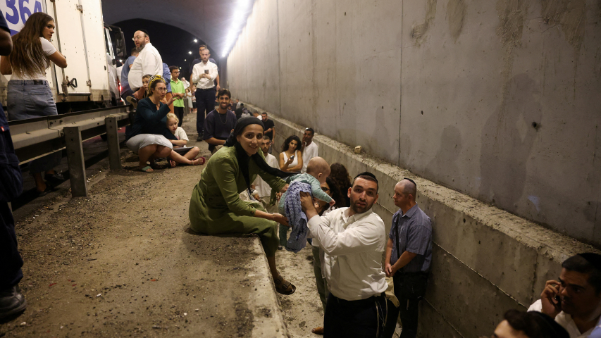 La gente se refugia durante una sirena de ataque aéreo después de que Irán disparara una salva de misiles balísticos, en el centro de Israel.
