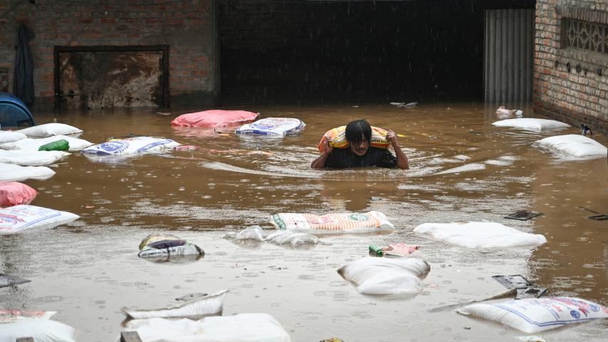 Un hombre trata de sacar sus cosas mientras va por el agua.