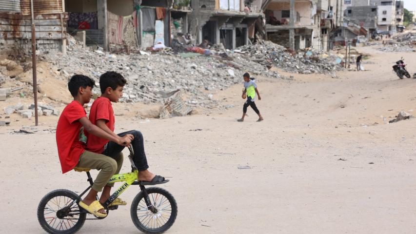 Children ride a bicycle across a war-devastated street in Gaza City on October 2, 2024, amid the ongoing war between Israel and the Palestinian Hamas militant group. (Photo by Omar AL-QATTAA / AFP)