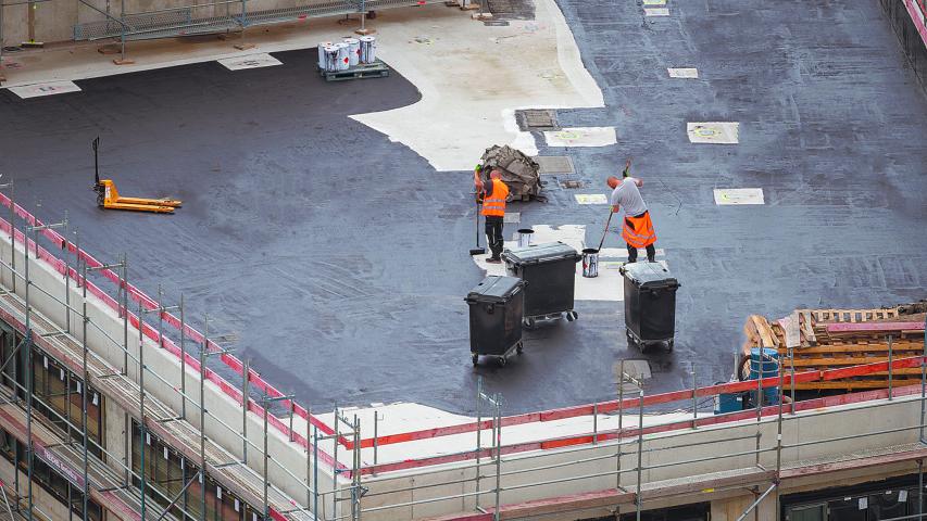 Roofer painting flat roof of a commercial building.