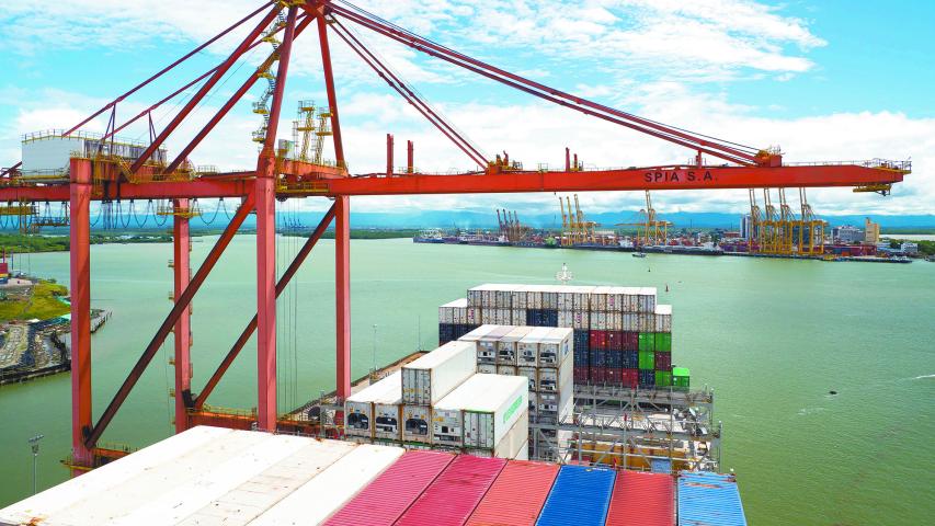 Buenaventura, Colombia - 11.28.22 Ultra large container ship have loading discharging operations in container terminal with gantry cranes. View of forward part and container terminal.