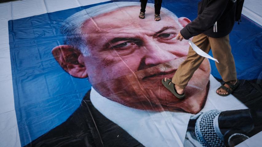 A demonstrator walks on a banner with a portrait of Israel's Prime Minister Benjamin Netanyahu during a pro-Palestinian rally on the eve of the first anniversary of the Israel-Hamas conflict, in Jakarta on October 6, 2024. (Photo by Yasuyoshi CHIBA / AFP)