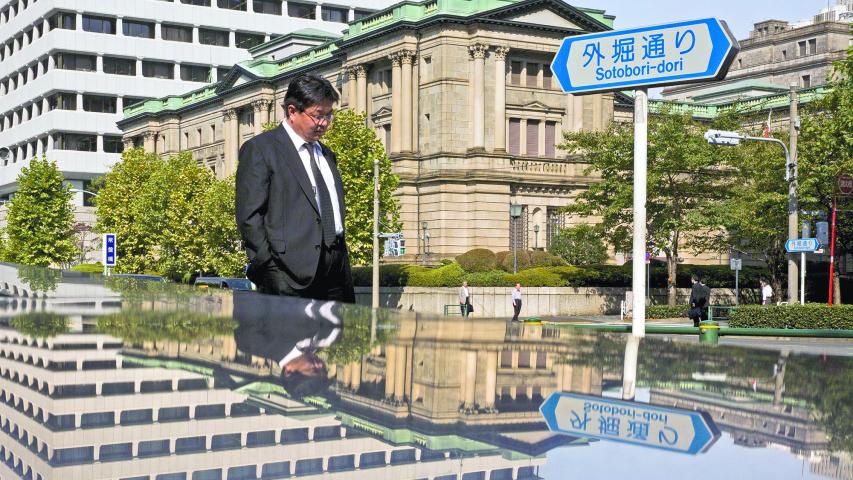 A man walks past the Bank of Japan (BOJ) building in Tokyo, in this October 30, 2015 file photo. Japan's central bank, which dominates the domestic bond market, has begun to call the shots in the equity market as well -- to the point where asset managers are looking to design investment funds with the Bank of Japan in mind.     REUTERS/Thomas Peter/Files