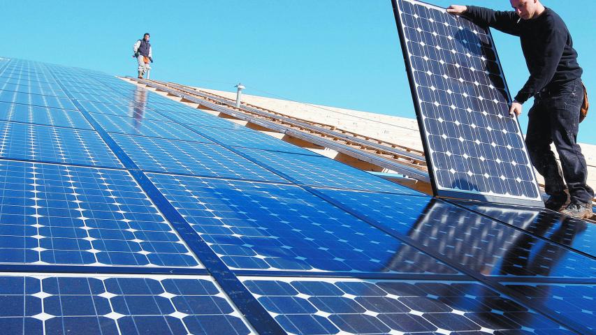 FILE PHOTO: Workers install solar panels on what will be the world's biggest integrated solar panel roof, 36,000 square metres spread over five hangars, at a farm in Weinbourg, Eastern France February 12, 2009.   REUTERS/Vincent Kessler/File Photo