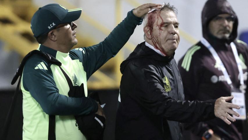 Mexico's coach, Javier Aguirre (R), is helped by an assistant after being injured in the head when he was hit by an object thrown from the bleachers at the end of the National League of Concacaf quarterfinal first leg match between Honduras and Mexico at the Francisco Morazan stadium in San Pedro Sula, Honduras, on November 15, 2024. (Photo by Jhony MAGALLANES / AFP)