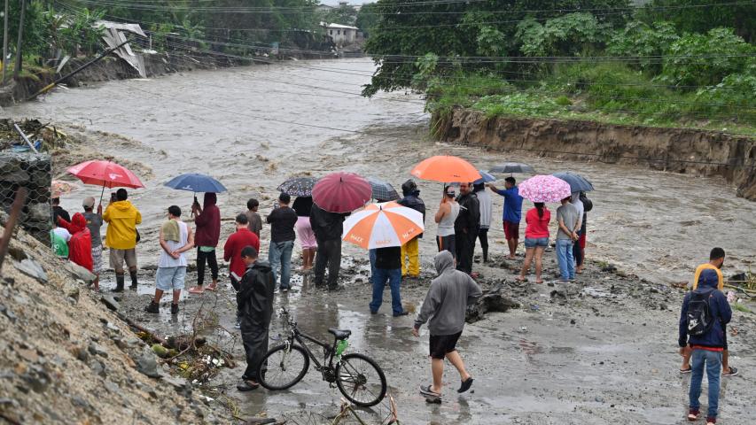 Personas damnificadas observan un arroyo inundado cerca de San Pedro Sula, Honduras.