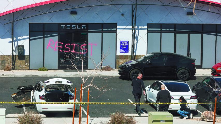 LAS VEGAS, NEVADA - MARCH 18: Investigators look over the scene at a Tesla Collision Center after an individual used incendiary devices to set several vehicles on fire on March 18, 2025 in Las Vegas, Nevada. The Las Vegas Metropolitan Police Department said that five Teslas were damaged and believe that the suspect fired three rounds from a firearm at the vehicles and spray painted the word "RESIST" on the entrance. Ethan Miller/Getty Images/AFP (Photo by Ethan Miller / GETTY IMAGES NORTH AMERICA / Getty Images via AFP)
