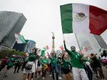 Aficionados del futbol celebrando con playeras de la Selección Mexicana en las inmediaciones del Ángel de la Independencia en la Ciudad de México.