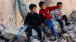 Niños palestinos desplazados se sientan sobre los escombros de un edificio destruido, en la ciudad de Gaza.