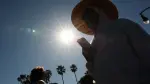 Una persona lleva un sombrero para protegerse del sol matutino mientras camina por The Strand en Redondo Beach, California.