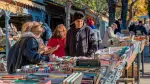 Gente revisando libros en los puestos de segunda mano en la Cuesta de Moyano de Madrid.