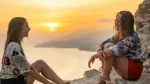 Dos amigas conversan frente a un bello atardecer. monshtein/Shutterstocl