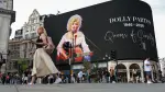 Unas personas pasan junto a un homenaje a la cantante estadounidense de música country Dolly Parton en Piccadilly Circus, un día después del anuncio de su fallecimiento a los 80 años, en Londres.