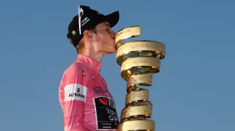 El ciclista danés Jonas Vingegaard, del equipo Visma Lease a Bike, con el maillot rosa de líder de la clasificación general, besa el trofeo mientras celebra en el podio tras ganar el Giro de Italia 2026.