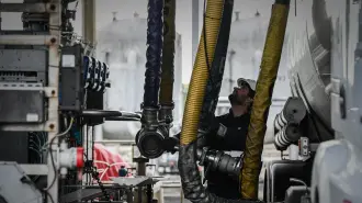 Conductor de camión conecta un brazo de carga de combustible a su camión cisterna en una terminal petrolera.